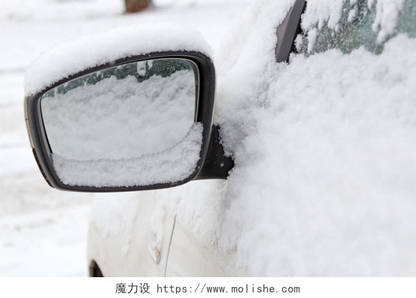 被大雪覆盖的小汽车白雪覆盖的侧面镜子的汽车特写。冬季汽车